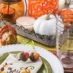 Close up of tableset with colorful plates, silverware and center piece arrangement for Thanksgiving party.