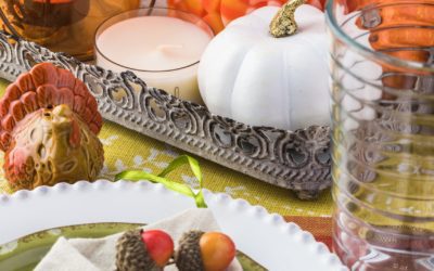 Close up of tableset with colorful plates, silverware and center piece arrangement for Thanksgiving party.