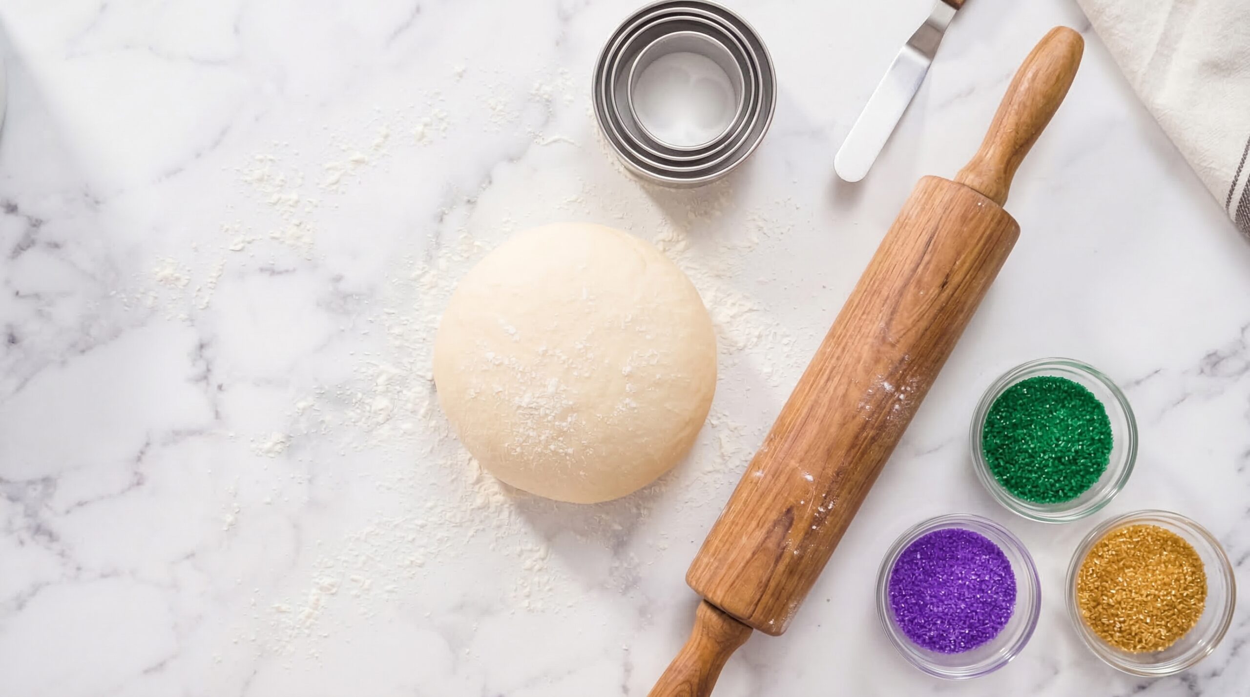 Professional yeast dough prep with a rolling pin and metal cutters on marble