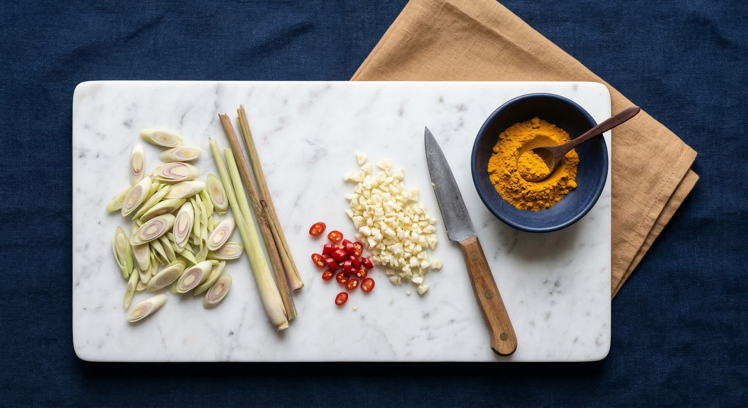 Fresh lemongrass, garlic, and turmeric prepared for an eggplant stew