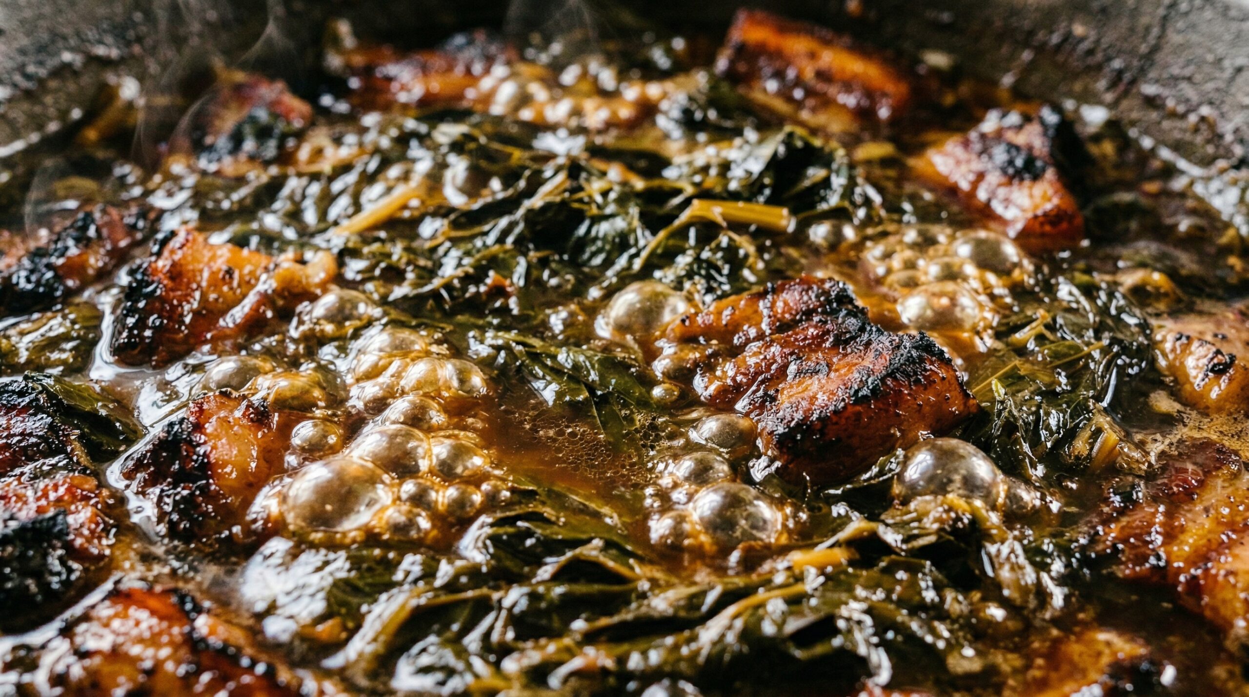 Dark, syrupy collard greens and thick, caramelized chunks of slow-roasted pork belly bubbling in a cast-iron Dutch oven